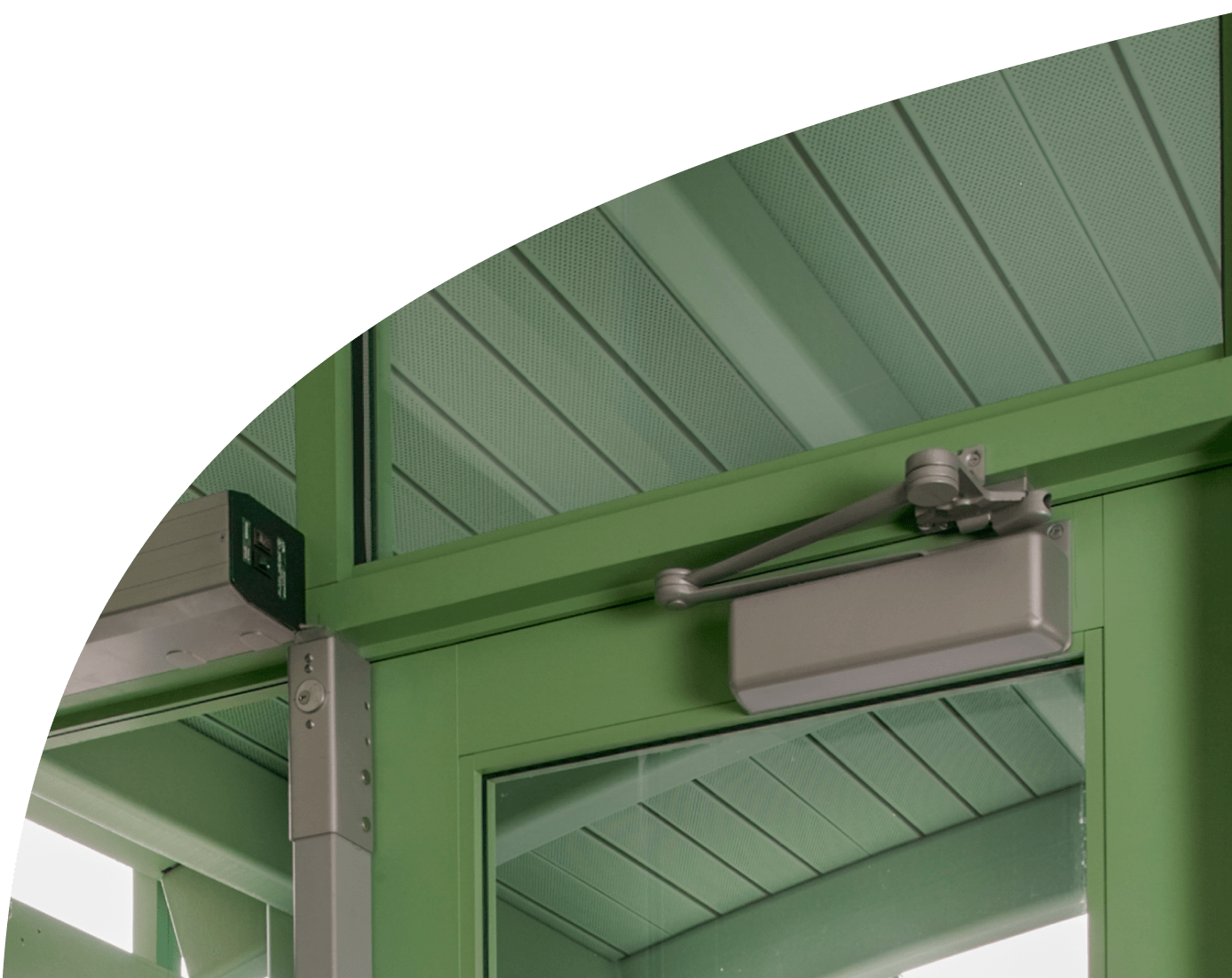 A trendy green commercial door with a door closer mounted to its top