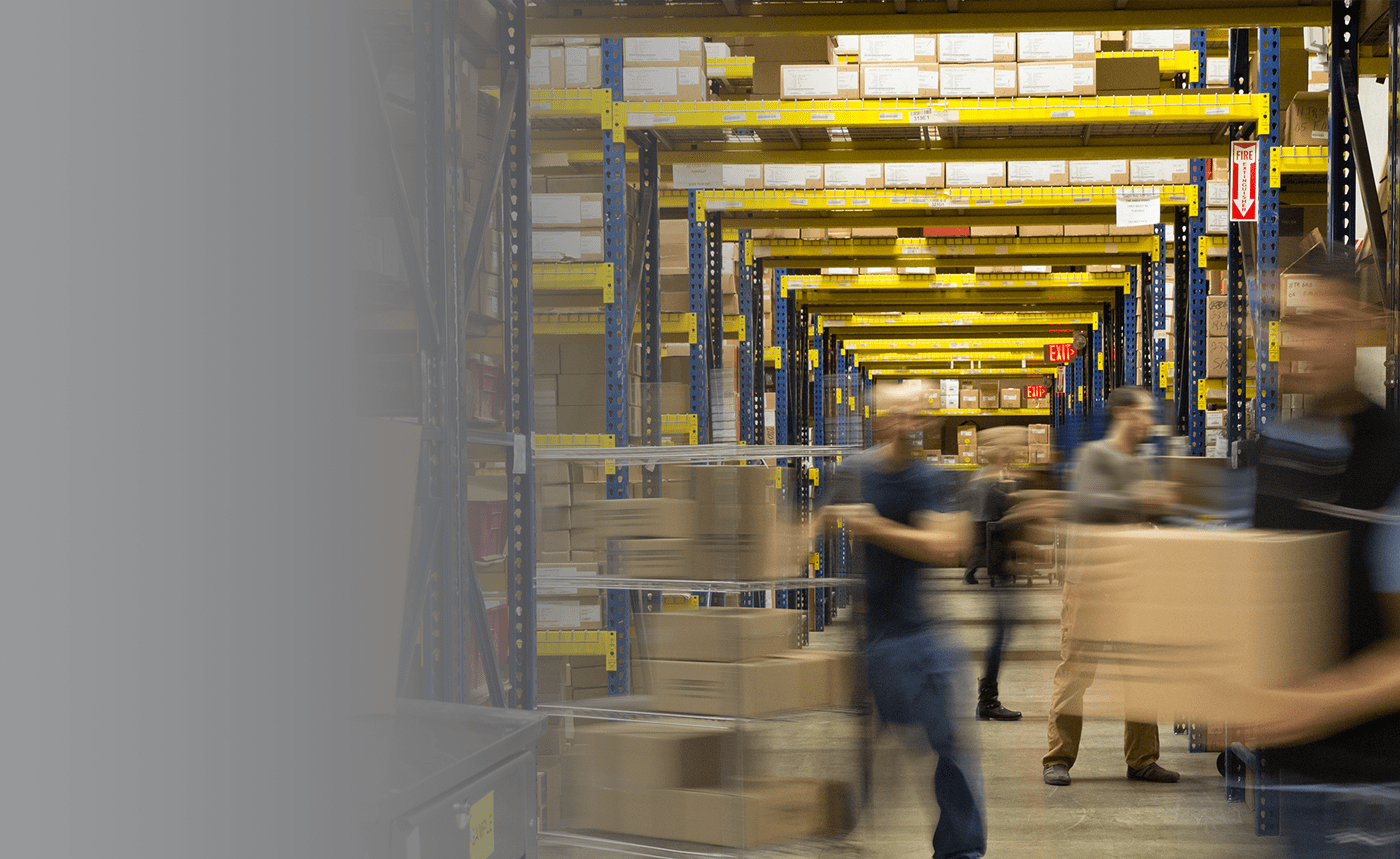 A man pushing a cart with boxes through a warehouse