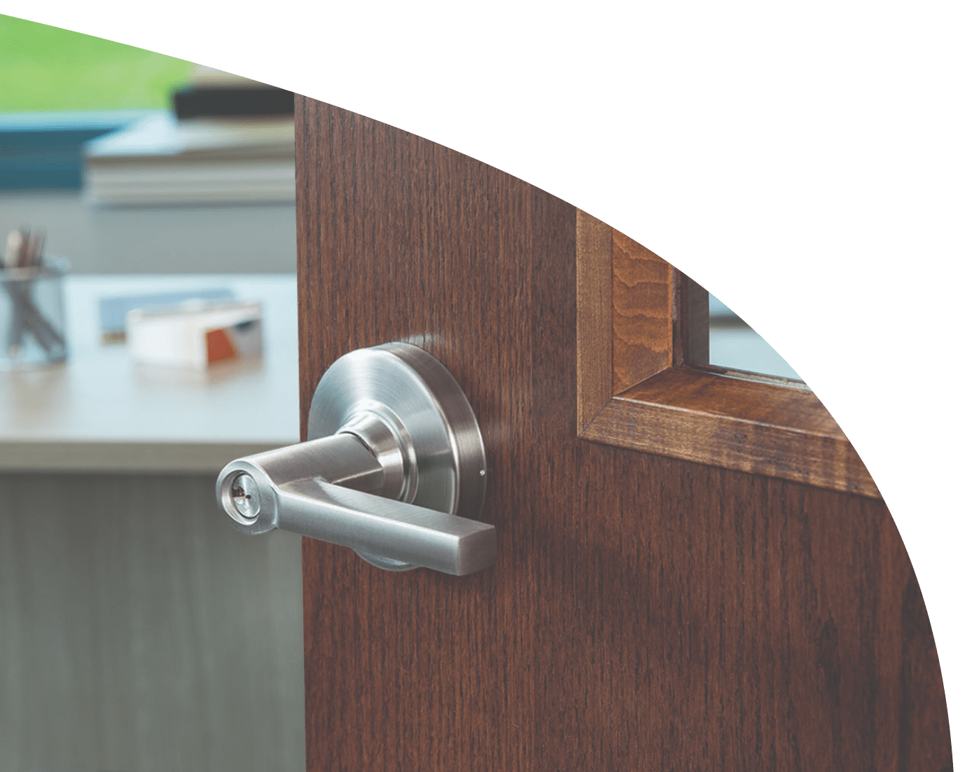 A brushed aluminum locking door handle on a rich, dark-wood door.