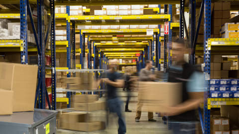 Busy warehouse employees moving products in boxes